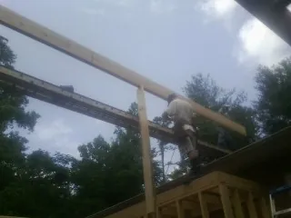 Carpenter setting a ridge beam over a new addition frame — Ice Dam Removal by Roofing Brothers in Conifer