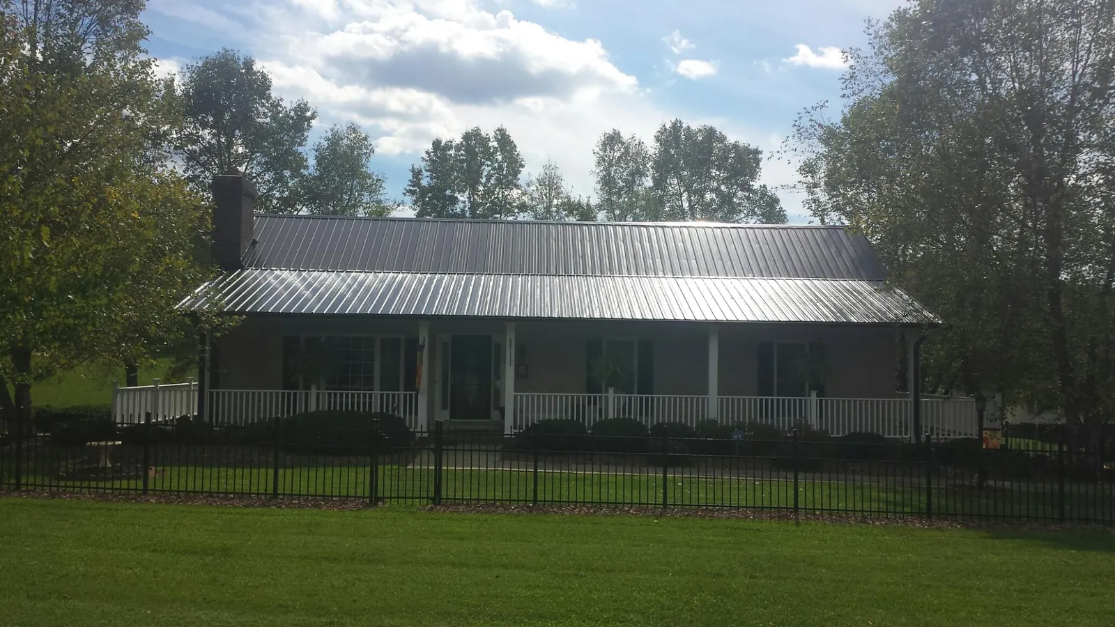 Gray metal roof on a brick ranch with a full width front porch — Gutter Guard Installation work by our crew in Conifer