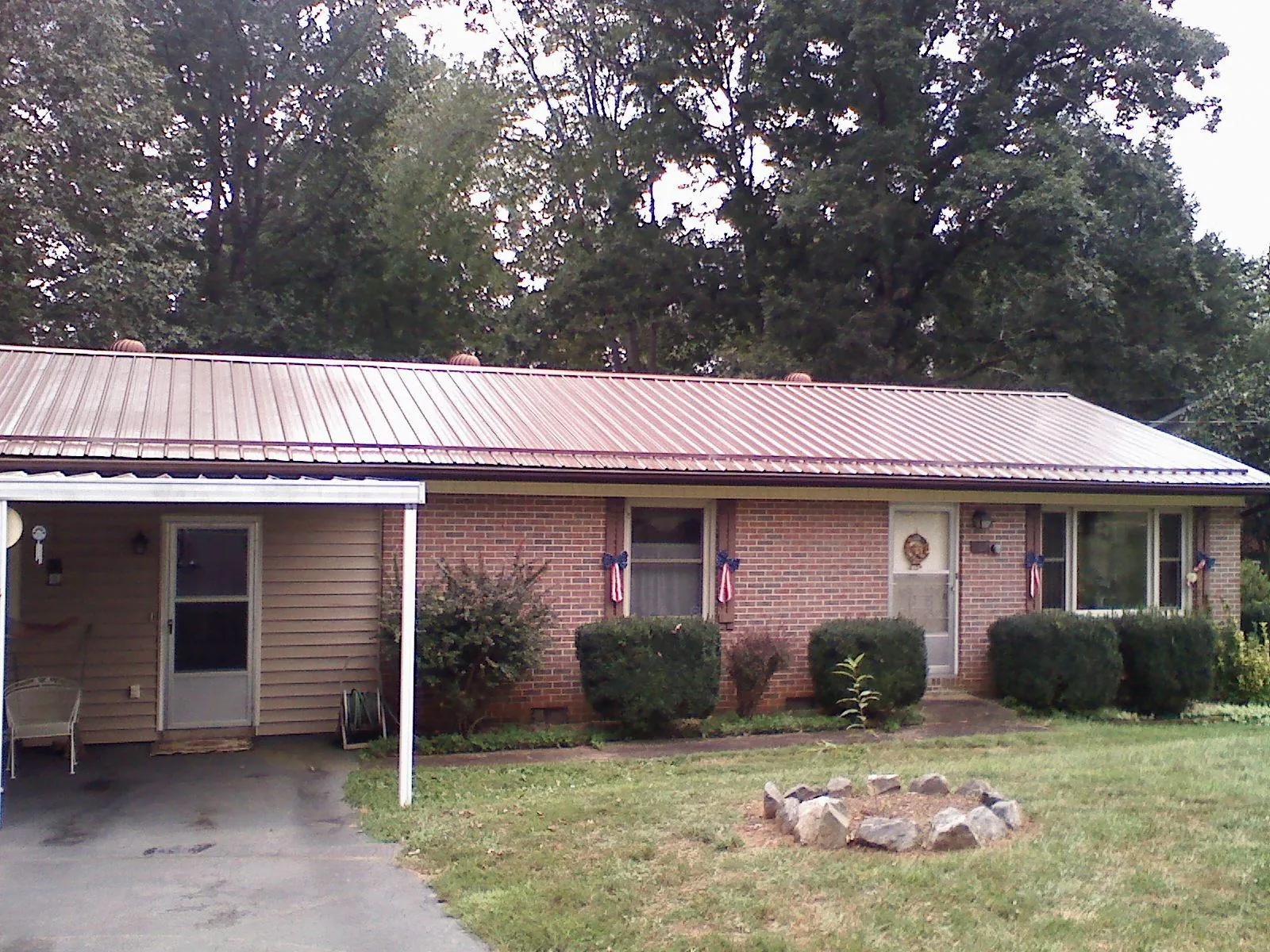 Bronze metal roof and carport on a brick ranch home — Roof Repair work by our crew in Conifer