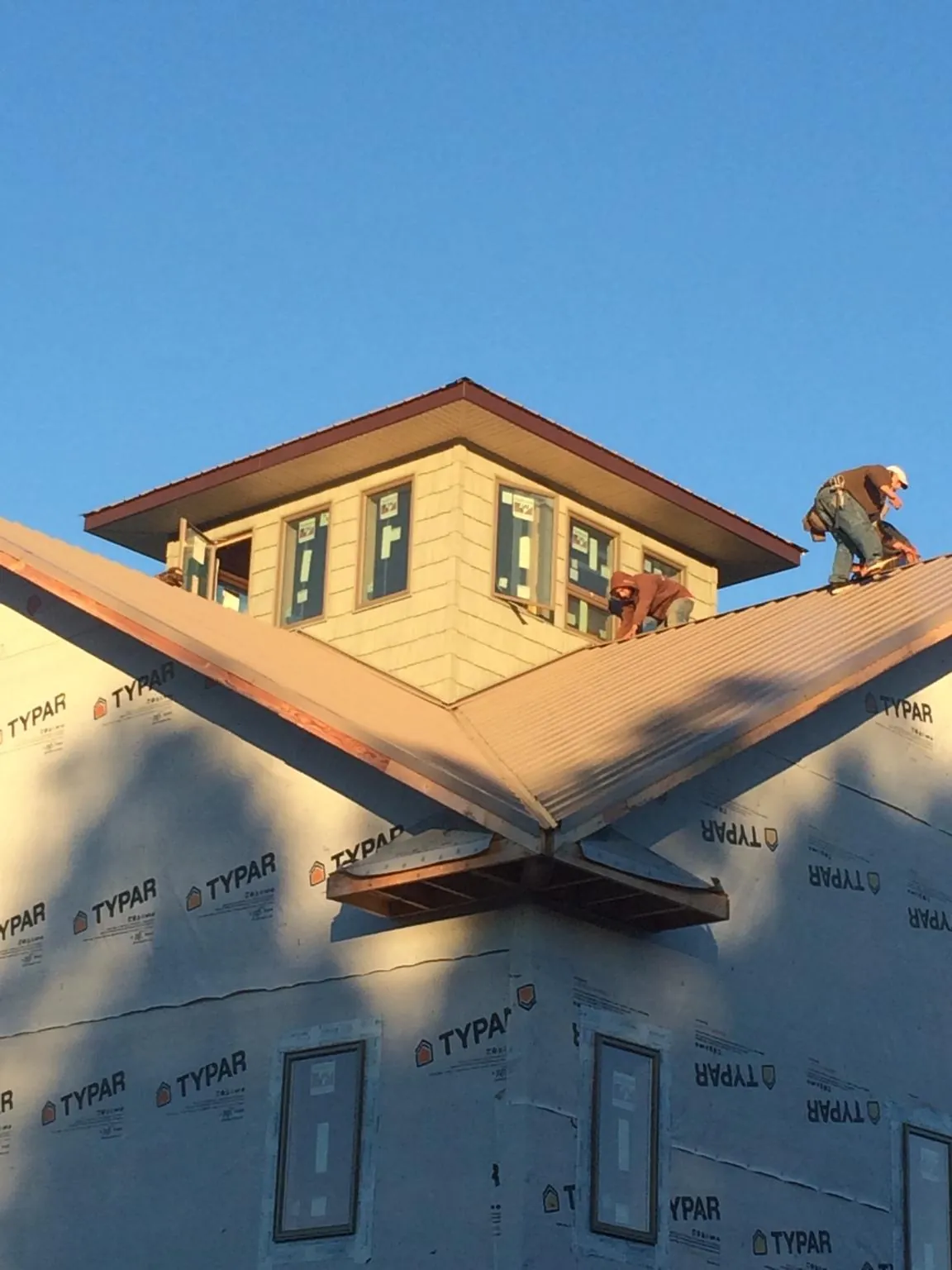 Roofers working around a rooftop cupola on a new metal roof at sunset — Roof Waterproofing in Conifer by Roofing Brothers